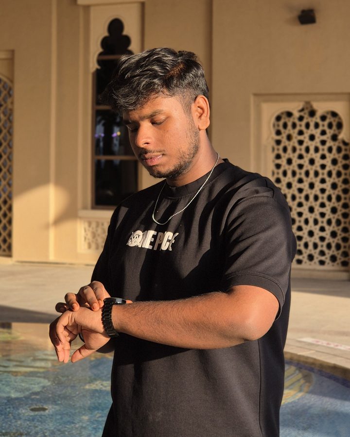 Sidharth Gopakumar in a black T-shirt, checking his watch in warm evening light